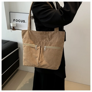 Detailed side view of khaki corduroy tote bag with dual zipper pockets on model