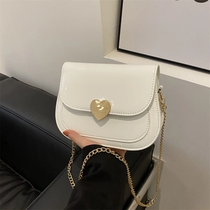 White patent leather saddle bag with golden heart clasp and chain strap for women