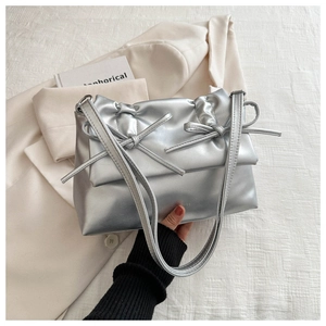 Detail view of silver bow-knot handbag with metallic texture and pleated design