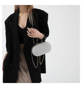 Silver glitter evening clutch with gold bow clasp and chain handle worn with a black suit