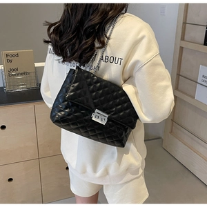 Detail of black quilted leather shoulder bag with silver chain strap and metal swivel lock