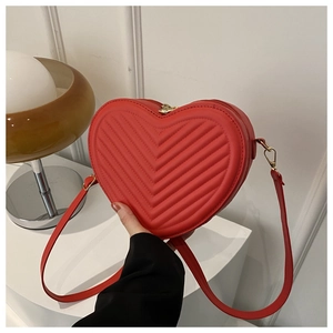 Detail of red heart-shaped shoulder bag with V-quilted texture and gold hardware