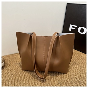 Minimalist brown PU leather tote bag with vertical stitching on a textured surface