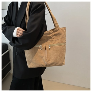 Detailed macro view of khaki corduroy tote bag with dual zipper pockets and strap