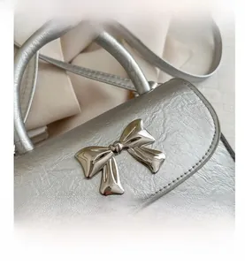 Macro detail of silver bow metallic buckle and lychee grain leather on mini handbag