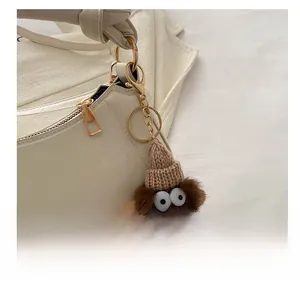 Detailed view of a plush monster bag charm with knit hat on an off-white shoulder bag