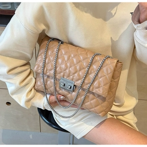 Detail of apricot quilted chain bag with silver buckle and elegant embroidery texture