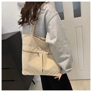 Detail of beige corduroy tote bag showing front zip pockets and textured fabric