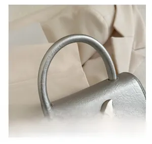 Detailed view of silver bow handle bag with metallic decoration and PU leather texture
