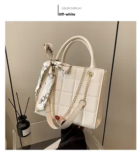 Close-up of cream quilted handbag with elegant silk scarf and gold chain strap detail