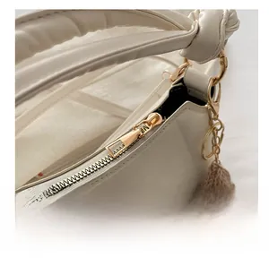 Detail of smooth gold zipper and fine stitching on cream faux leather saddle bag