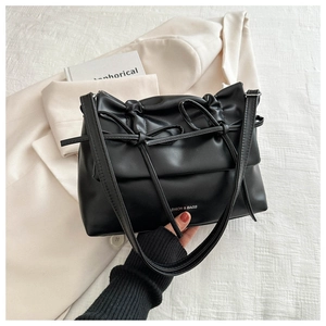 Detail of black faux leather crossbody bag featuring bow drawstring and fashion lettering