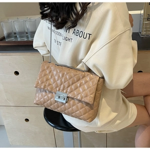 Detail of beige quilted chain bag with silver metallic clasp and diamond stitching