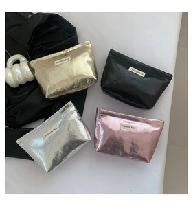 Flat lay view of four metallic cosmetic bags in gold, black, silver, and pink finishes