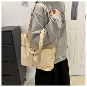 Detail shot of beige corduroy tote bag with vertical stripes and front zipper pocket