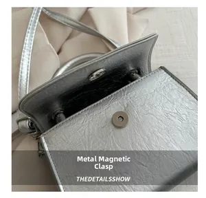 Detail shot of the silver metallic magnetic closure on a stylish bow handbag