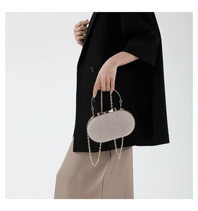 Detail of elegant evening clutch featuring metallic texture and gold ring handle