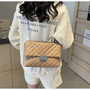 Detail view of beige quilted crossbody bag with silver chain strap and twist lock