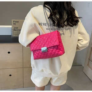 Macro shot of bright pink quilted crossbody bag with silver buckle and chain strap