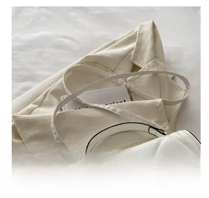 Detail of white quilted crossbody bag featuring a golden pearl-encrusted heart clasp