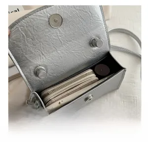 Interior view showing the capacity of a silver bow handbag with phone and cosmetics