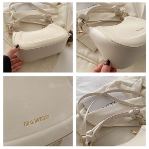 Close-up of cream shoulder bag with golden logo, zippers, and hardware details