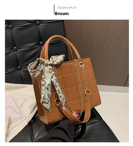 Close-up of brown quilted tote bag featuring a chain strap and scarf wrapped handle