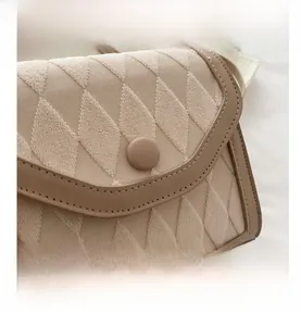Macro detail of beige quilted fabric texture and leather edging on retro handbag