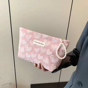 Pink heart-patterned makeup bag with quilted texture and decorative pearl handle