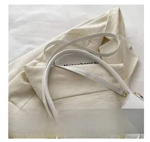 Detailed close-up of white leather shoulder bag with golden bow buckle on a suit jacket