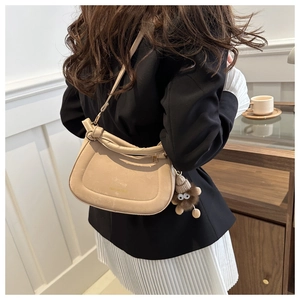 Detail of beige leather crossbody bag with Mini Design logo and plush monster charm