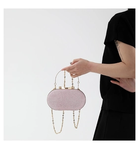 Pink sequin evening bag featuring a gold bow clasp and metal chain held by a person