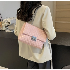Detailed view of a pink quilted chain bag with silver buckle worn on a model shoulder