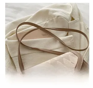 Detail of rhombic quilted crossbody bag with adjustable leather strap and gold hardware