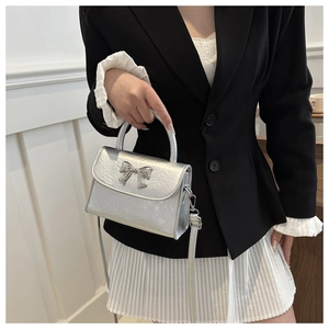 Detail of silver mini crossbody bag with metallic texture and bow-knot metal buckle