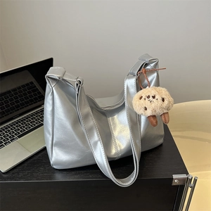 Silver metallic textured leather tote bag with wide shoulder strap and plush charm