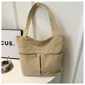 Detailed macro view of beige corduroy tote bag with dual front metal zipper pockets