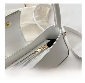Detail of a white crossbody bag showing the smooth golden zipper and magnetic closure