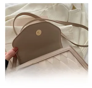 Detail view of the secure golden magnetic snap closure on a quilted beige shoulder bag