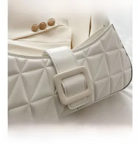 Détail du sac à main matelassé blanc avec surpiqûres triangulaires et boucle carrée large