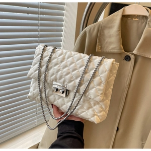 Detail shot of white quilted crossbody bag with silver twist lock and chain strap