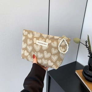 Brown heart print canvas makeup bag with pearl zipper pull and fashion bag label