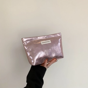 Pink metallic makeup bag with ripple texture and Fashion Bag label held by hand