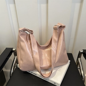 Pink minimalist faux leather tote bag with wide strap on a chair, minimalist urban style