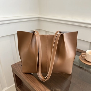 Minimalist caramel leather tote bag with vertical stitching and large capacity in home setting