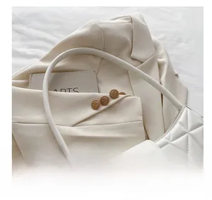 Détail du sac à bandoulière beige matelassé avec texture en losange et boucle carrée