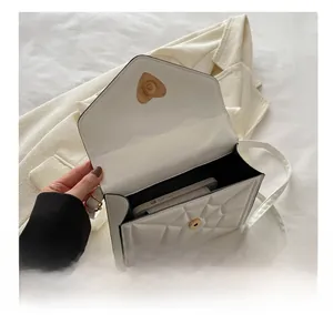 Interior detail of white quilted envelope bag with gold heart-shaped magnetic clasp closure