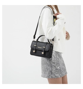 Detail of classic black leather crossbody bag with gold hardware and white text print