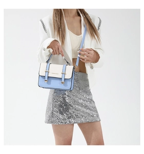 Detail of blue and beige contrast color square bag with gold buckle straps and fashion logo