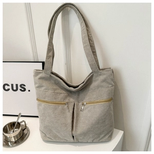 Close-up of light grey corduroy tote bag with double zippered front pockets and wide straps